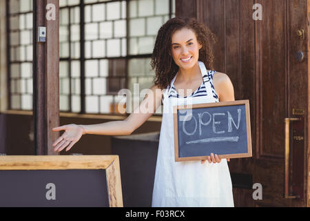 Lächelnd Kellnerin zeigt Tafel mit Schild "geöffnet" Stockfoto