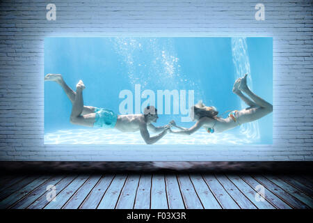 Zusammengesetztes Bild des süße paar halten die Hände unter Wasser im Schwimmbad Stockfoto