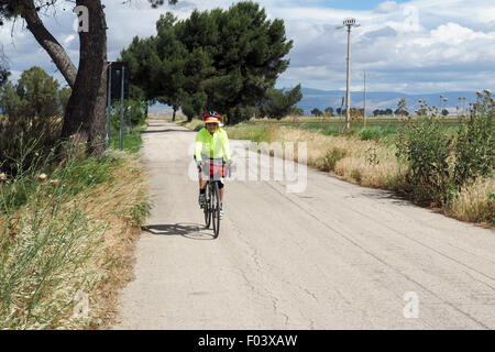 Weibliche touring Radfahrer Fahrrad auf einer Landstraße in Apulien, Italien. Stockfoto