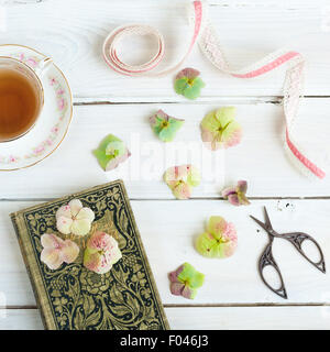 Stillleben mit Teetasse, altes Buch, Hydrangea blüht, Farbband und Stickerei Schere Stockfoto