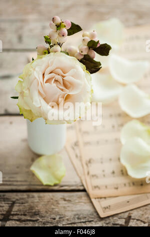 einzelne Elfenbein Rose mit Snowberries und Notenpapier im Hintergrund Stockfoto