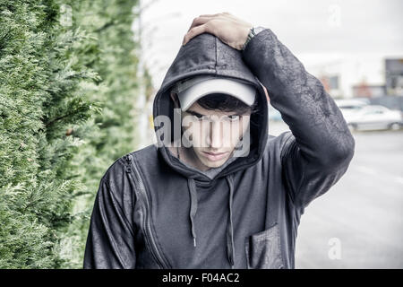 Hübscher junger Mann in schwarzer Hoodie Pullover stehen im Freien in Straße Blick in die Kamera, Haube übergeben Stockfoto