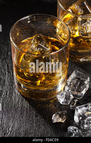 Brille von scotch Whisky mit Eis auf schwarzen Steintisch Stockfoto