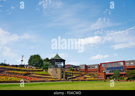 Tamworth Castle Gardens, Musikpavillon und Blume Betten in voller Blüte mit Ankerside Shopping Centre, Staffordshire Stockfoto