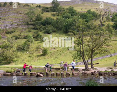 Familie Kreuzung die Trittsteine über den Fluss Dove in Dovedale, Derbyshire Peak District, England, Großbritannien Stockfoto