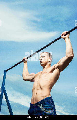 Nahaufnahme von starken Athleten Pull-up am Reck zu tun. Mans Fitness mit blauen Himmel im Hintergrund und Freifläche rund um Hallo Stockfoto