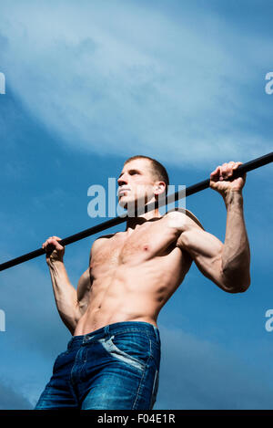 Nahaufnahme von starken Athleten Pull-up am Reck zu tun. Mans Fitness mit blauen Himmel im Hintergrund und Freifläche rund um Hallo Stockfoto