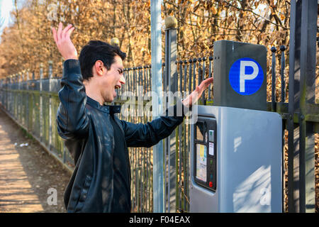 Junger Mann wütend auf Parkschein aus dem Ticketschalter an der Seite einer Straße nach seiner Zahlung verzichtet werden Stockfoto