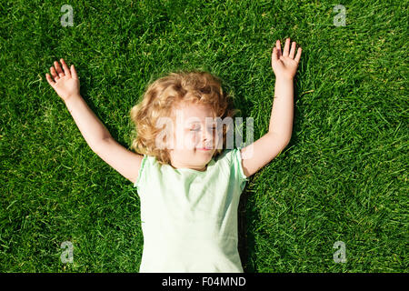 Entzückendes kleine Mädchen liegen auf dem Rasen, Ansicht von oben träumen Stockfoto