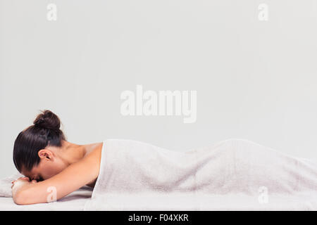 Seite Ansicht Porträt einer Frau liegend auf der Massageliege in ein Wellness-Center, isoliert auf weißem Hintergrund Stockfoto