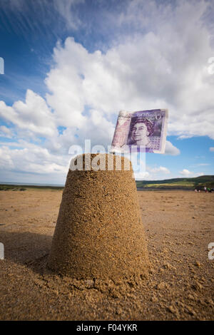 Konzept-Foto von eine Sandburg mit einem £20 Notizkennzeichen am UK Strand zu zeigen, die Kosten für die Schulferien Stockfoto