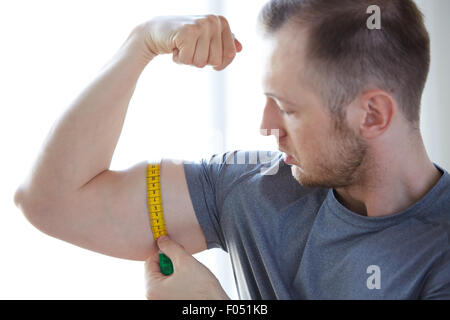 Nahaufnahme von männliche Hände mit Klebeband Messung Bizeps Stockfoto