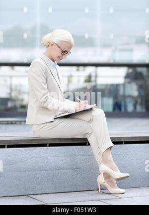 junge lächelnde Geschäftsfrau mit Notepad im freien Stockfoto