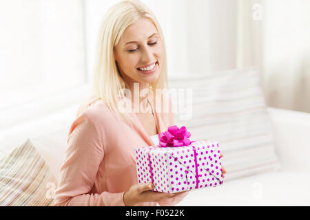 lächelnde Frau mit Geschenk-Box zu Hause Stockfoto