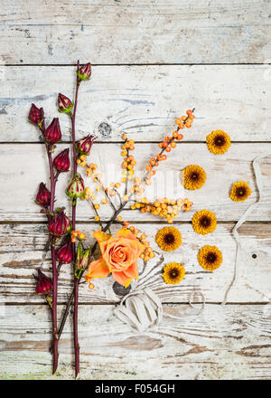 Blick von oben auf das stilvolle Arrangement von Herbstbeeren und Blumen in warmen Farben auf einem rustikalen hölzernen Hintergrund Stockfoto