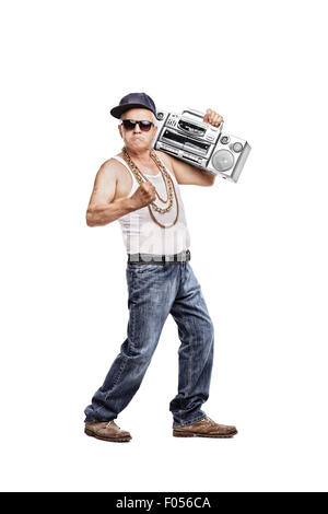 In voller Länge Portrait von einem reifen Mann in Hip-Hop-Outfit hält einen Ghetto-Blaster und schaut in die Kamera Stockfoto