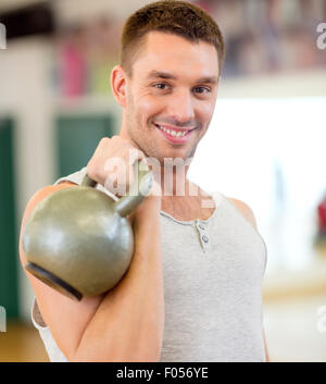 lächelnder Mann mit Kettlebell in Turnhalle Stockfoto