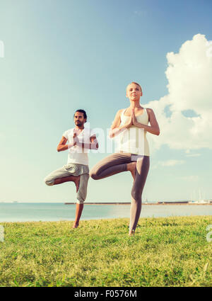 Lächelndes Paar machen Yoga Übungen im Freien Stockfoto