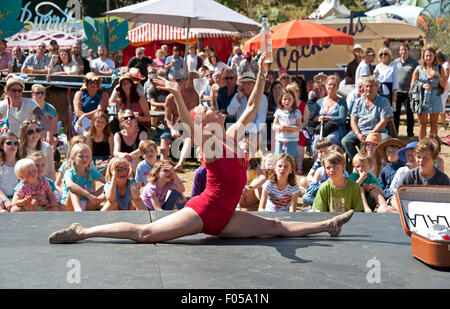 Familien beobachten einen akrobatischen Akt in der Sommersonne von Garküchen und Zelten am Hafen Eliot Festival Cornwall Stockfoto