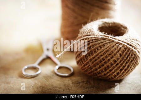 Schnur Kordel mit einer Schere auf rustikalen Holztisch Stockfoto
