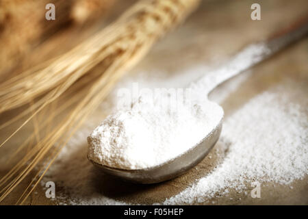 Weizenmehl in Dosierlöffel auf rustikalen Holztisch Stockfoto