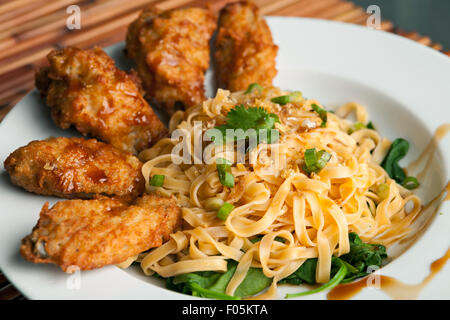 Chicken Wings mit Nudeln und Spinat Stockfoto