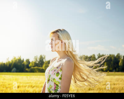 Schöne helle Haut Blonde tragen eines geblümten Kleid, Sommer Sonne, Gerstenfeld auf Hintergrund Stockfoto