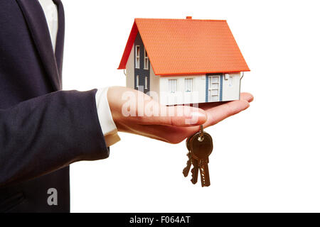 Immobilienmakler mit kleinem Haus und Schlüssel in der hand Stockfoto
