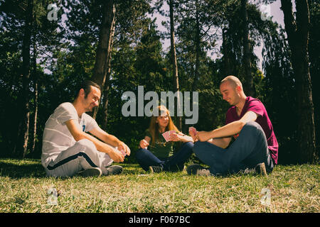 Drei Freunde, die Spaß von Spielkarten im Wald Stockfoto