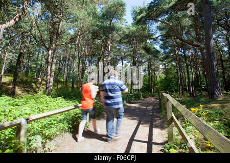 Formby Squirrel Reserve in der Nähe von Liverpool, Großbritannien. August 2015. Touristen, die das Formby Squirrel Reserve besuchen, um die roten Eichhörnchen in ihrer natürlichen Umgebung zu sehen und kilometerlange Küstenwanderungen an einem herrlichen Sommernachmittag zu genießen. Autos und Besucher standen Schlange, um einzusteigen, damit sie einen atemberaubenden Blick auf das Meer oder ein Picknick genießen konnten. Ein Paar macht einen Küstenspaziergang, um sich die faszinierende Küste von Formby anzusehen. Quelle: Cernan Elias/Alamy Live News Stockfoto