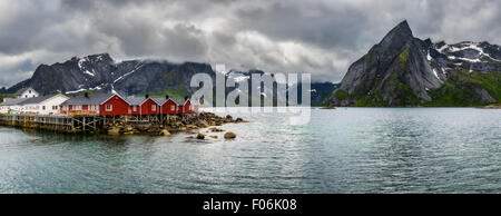 Panorama des Monte Olstind über die rote Fischerhütten genannt Fischerorten in Stadt von Hamnoy auf den Lofoten Inseln, Norwegen Stockfoto