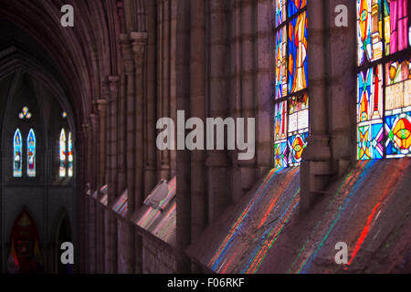 Wunderschöne Lichtreflexionen von der Glasmalerei im Inneren der Basilika del Voto Nacional. Eine römisch-katholische Kirche in Quito, Ecuador Stockfoto