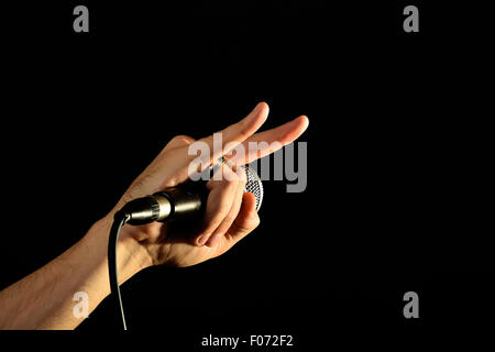 Männliche Hand mit Mikrofon mit Teufelshörnern Rock Blechschild auf schwarzem Hintergrund isoliert Stockfoto