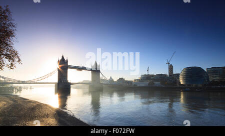 Die Sonne geht hinter der Tower Bridge, London, an einem klaren, kalten Novembermorgen mit leichten Nebel über der Themse Stockfoto