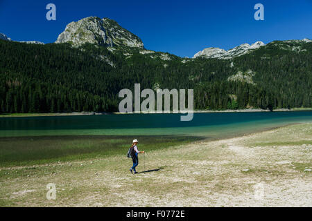 Frau Wanderer mit Rucksack und Wanderstock auf dem schwarzen See im Durmitor National Park, Montenegro, Balkan Stockfoto