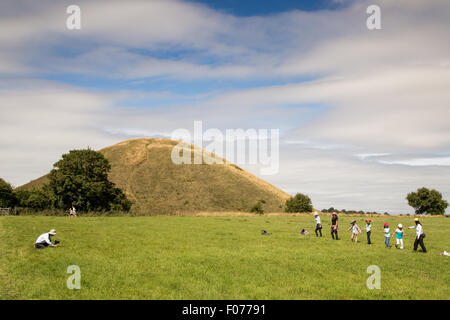 Avebury, Wiltshire, UK. 9. August 2015. Touristen genießen das Wetter als warme sonnige Bedingungen weiterhin Silbury Hill neolithischen Baudenkmal in die weiten offenen Ebenen des Wiltshire zu backen. Bildnachweis: Wayne Farrell/Alamy Live-Nachrichten Stockfoto