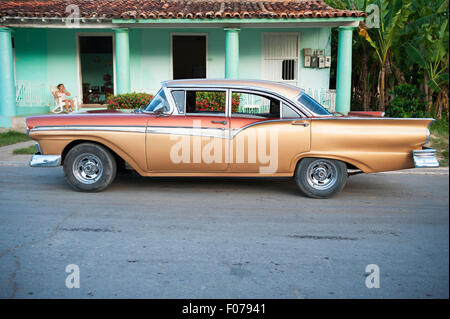 VINALES, Kuba - 20. Mai 2011: Klassische amerikanische Auto steht vor geparkt resident sitzt auf der Veranda eines einfachen Hauses. Stockfoto