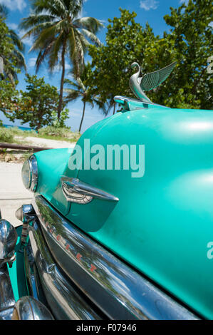 VARADERO, Kuba - 7. Juni 2011: Klassische amerikanische Auto steht geparkt vor Palmen auf der Straße neben dem Strand. Stockfoto