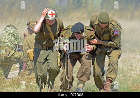 Eine Nachstellung des Zweiten Weltkriegs mit Sanitätern, die einem „verwundeten“ Para mit Sten Gun helfen. Soldat in Uniform Stockfoto