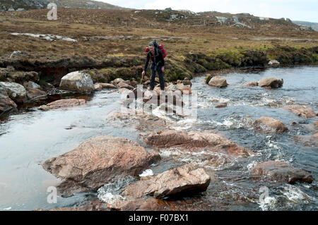 Walker, die Überquerung der Strath Cailleach Fluss, in der Nähe von Sandwood Bay, Cape Wrath Wildnis, Sutherland, Schottland, UK Stockfoto