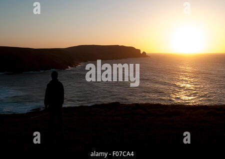 Ein Wanderer auf einer Klippe über der Bucht von Kearvaig bei Sonnenuntergang an der Nordküste östlich von Cape Wrath, Sutherland, Schottland, UK. Stockfoto