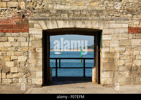 Blick durch die historische Stadtmauer in Old Portsmouth; Gateway mit Blick auf die Hafeneinfahrt mit einem kleinen Boot vorbei. Stockfoto