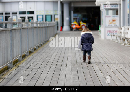 Ein Kind läuft eine Pier am Meer entlang Stockfoto