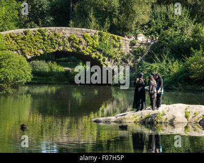 Muslimische Frauen in voller Burkas in den Teich und Gapstow Bridge, Central Park, New York Stockfoto