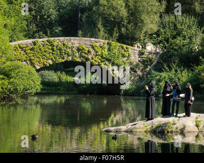 Muslimische Frauen in voller Burkas in den Teich und Gapstow Bridge, Central Park, New York Stockfoto