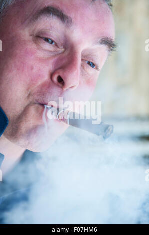 Ein Mann genießt eine Zigarre und macht lustige Gesichter während Rauchen Stockfoto