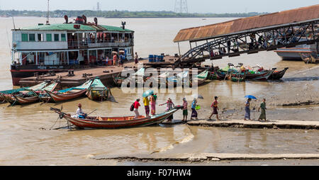 Passagiere von Bord von Fähre am Pier auf dem Yangon-Fluß in Yangon. Eine größere Riverboat und Gangway sind hinter ihnen. Stockfoto