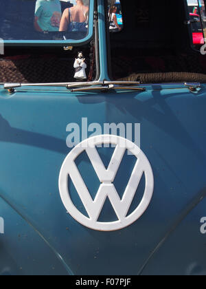 Ein VW-Emblem auf der Vorderseite des klassischen VW Wohnmobil. Die Fenster sind offen mit einem Kumpel Christus im Fenster Stockfoto