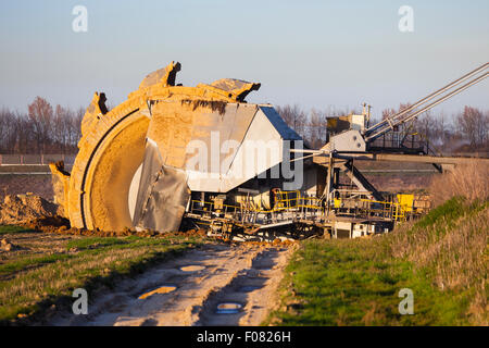 Einen riesigen Schaufelradbagger bei der Arbeit in einer Braunkohle pit mine mit einem Feldweg erkennbar, die im Vordergrund Stockfoto