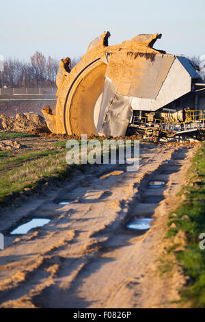 Einen riesigen Schaufelradbagger bei der Arbeit in einer Braunkohle pit mine mit einem Feldweg erkennbar, die im Vordergrund Stockfoto